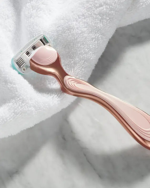 Rose gold razor on a white towel
