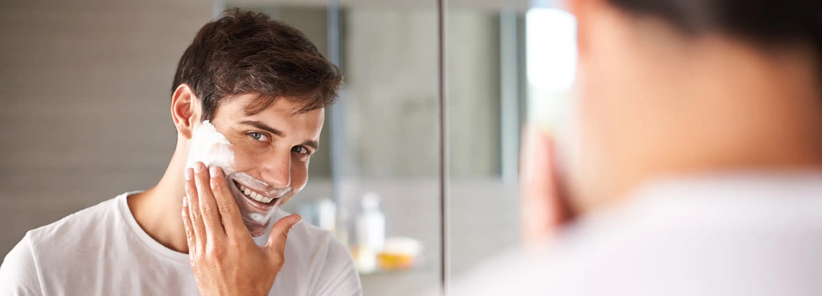 Man applying cream to his face in front of a mirror